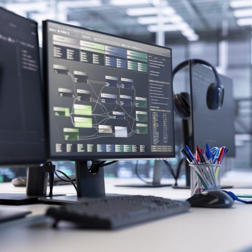Close up of programming language on PC displays on desk in server farm used for data processing requirements of AI workloads and neural network machine learning technology